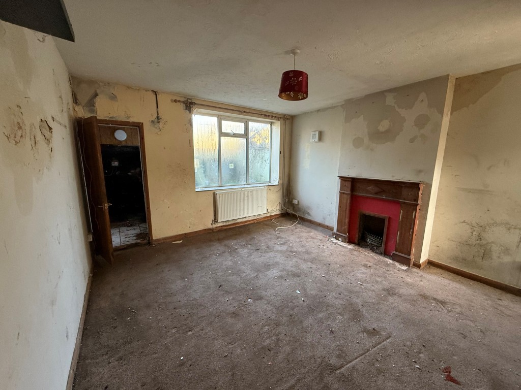Lot: 173 - THREE-BEDROOM TERRACED HOUSE FOR REFURBISHMENT LOCATED IN A CUL-DE-SAC - Ground floor lounge with window and doors leading to storage